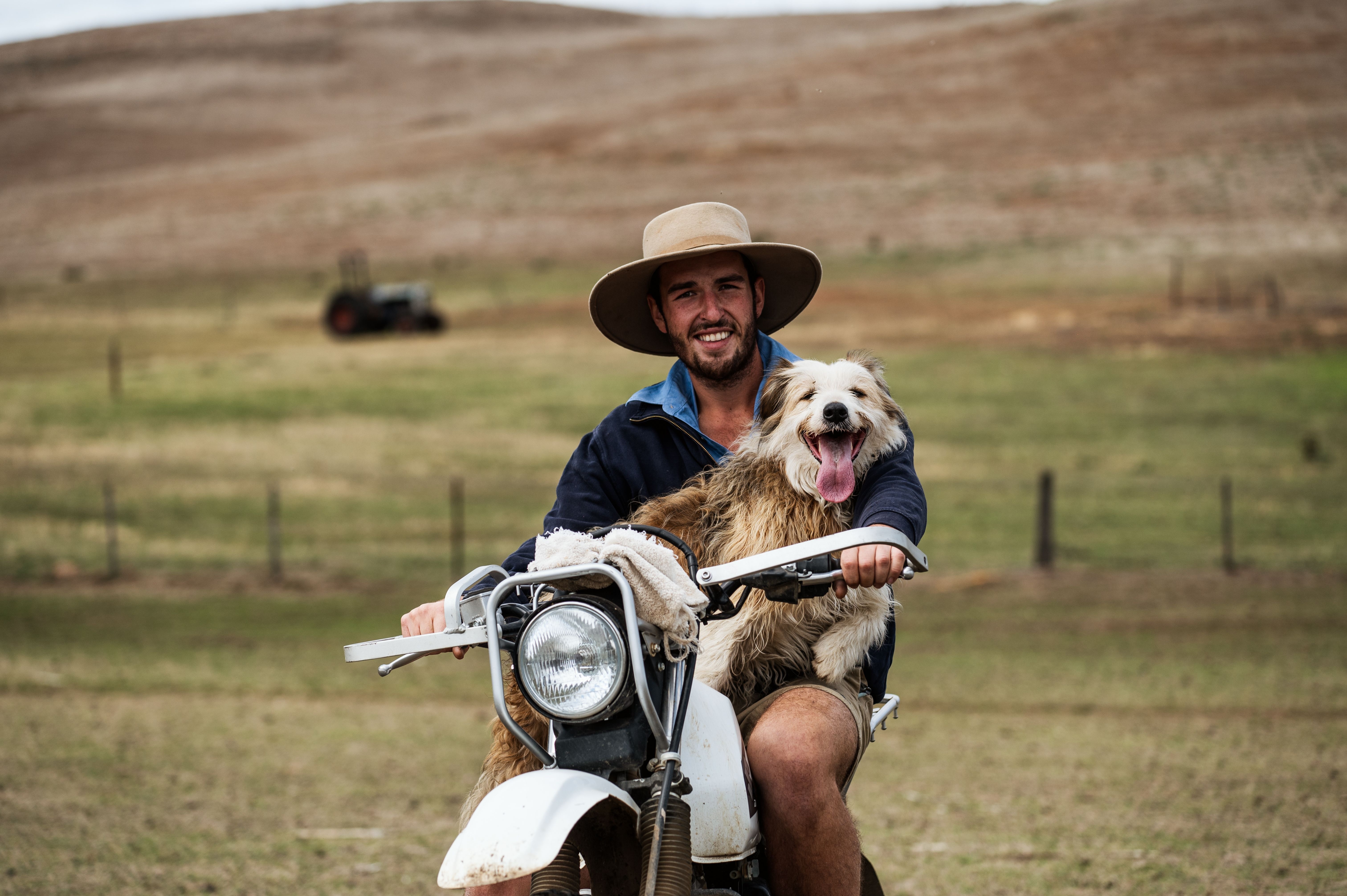 A farmer smiling with his working dog on a farm motorbike, Curringa Farm at Hamilton in Tasmania's Central Highlands
