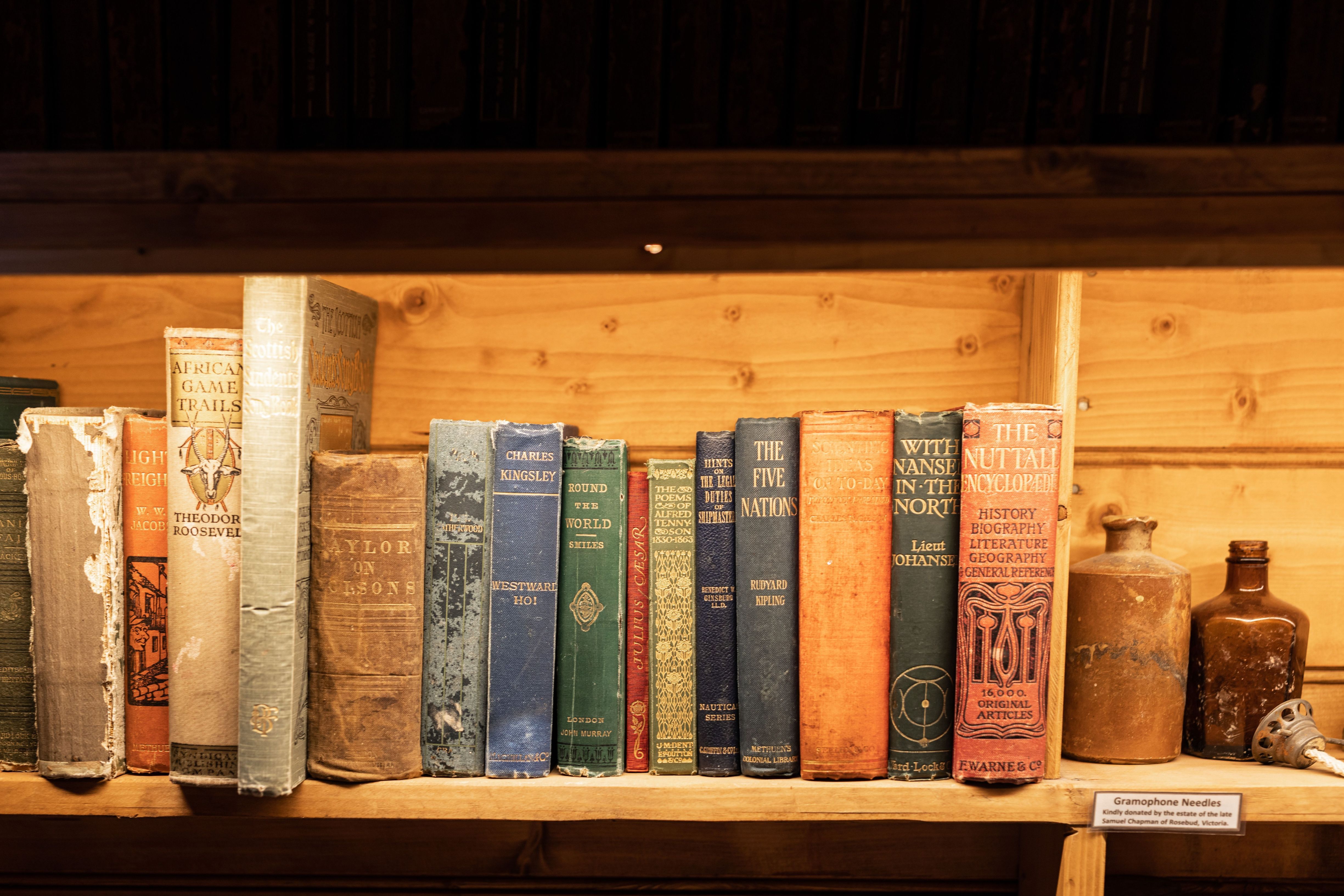 Mawson's Huts Replica Museum interior showing antique books and bottles on a wooden shelf, Hobart, Tasmania