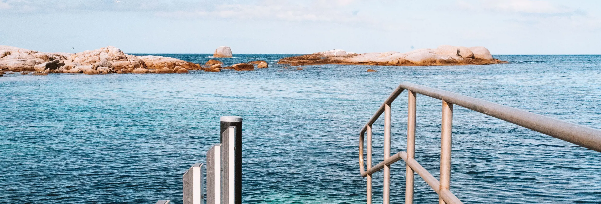 View from a jetty looking out across calm water toward granite outcrops, Coles Bay on Tasmania's East Coast