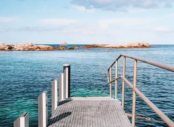 View from a jetty looking out across calm water toward granite outcrops, Coles Bay on Tasmania's East Coast