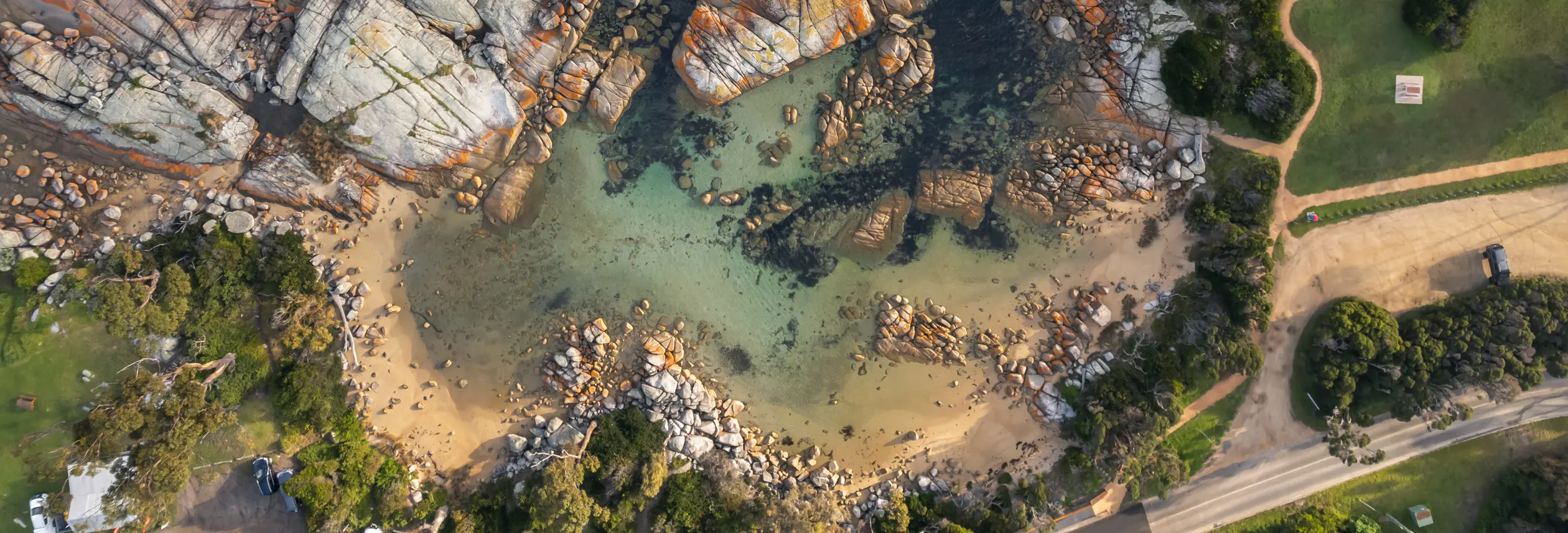 Aerial view of a sandy cove and granite boulders at The Gardens, larapuna / Bay of Fires area, Tasmania's East Coast