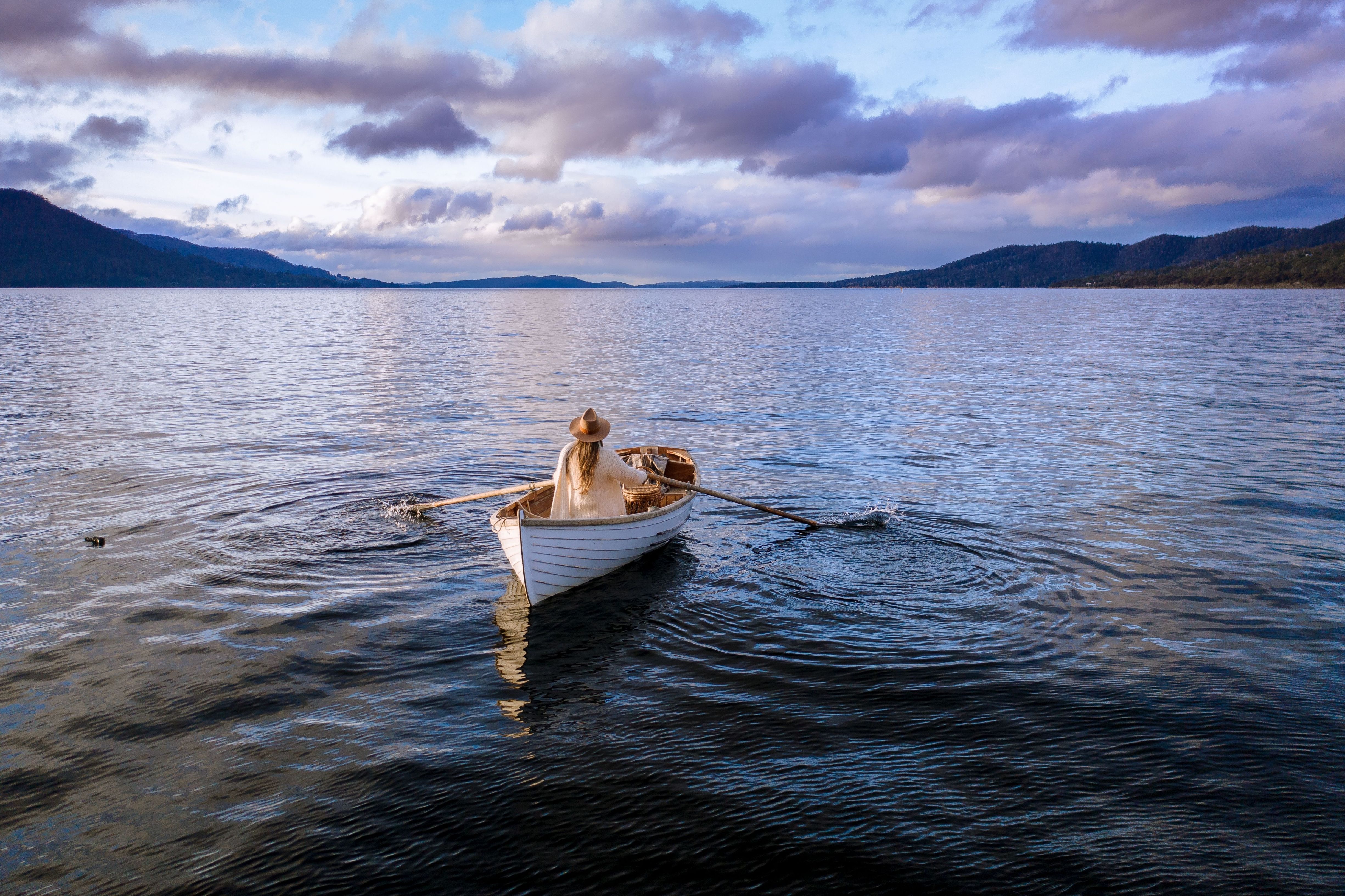 A person rowing a wooden boat on calm water at Satellite Island, D'Entrecasteaux Channel, Tasmania