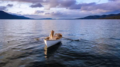 A person rowing a wooden boat on calm water at Satellite Island, D'Entrecasteaux Channel, Tasmania