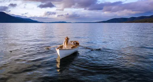 A person rowing a wooden boat on calm water at Satellite Island, D'Entrecasteaux Channel, Tasmania