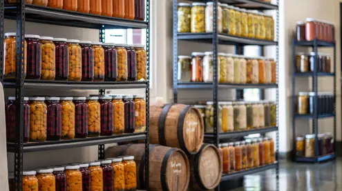 Shelves of preserved produce in glass jars and wooden barrels at The Agrarian Kitchen, New Norfolk, Tasmania