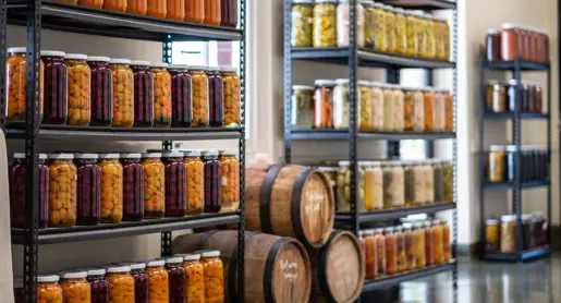 Shelves of preserved produce in glass jars and wooden barrels at The Agrarian Kitchen, New Norfolk, Tasmania