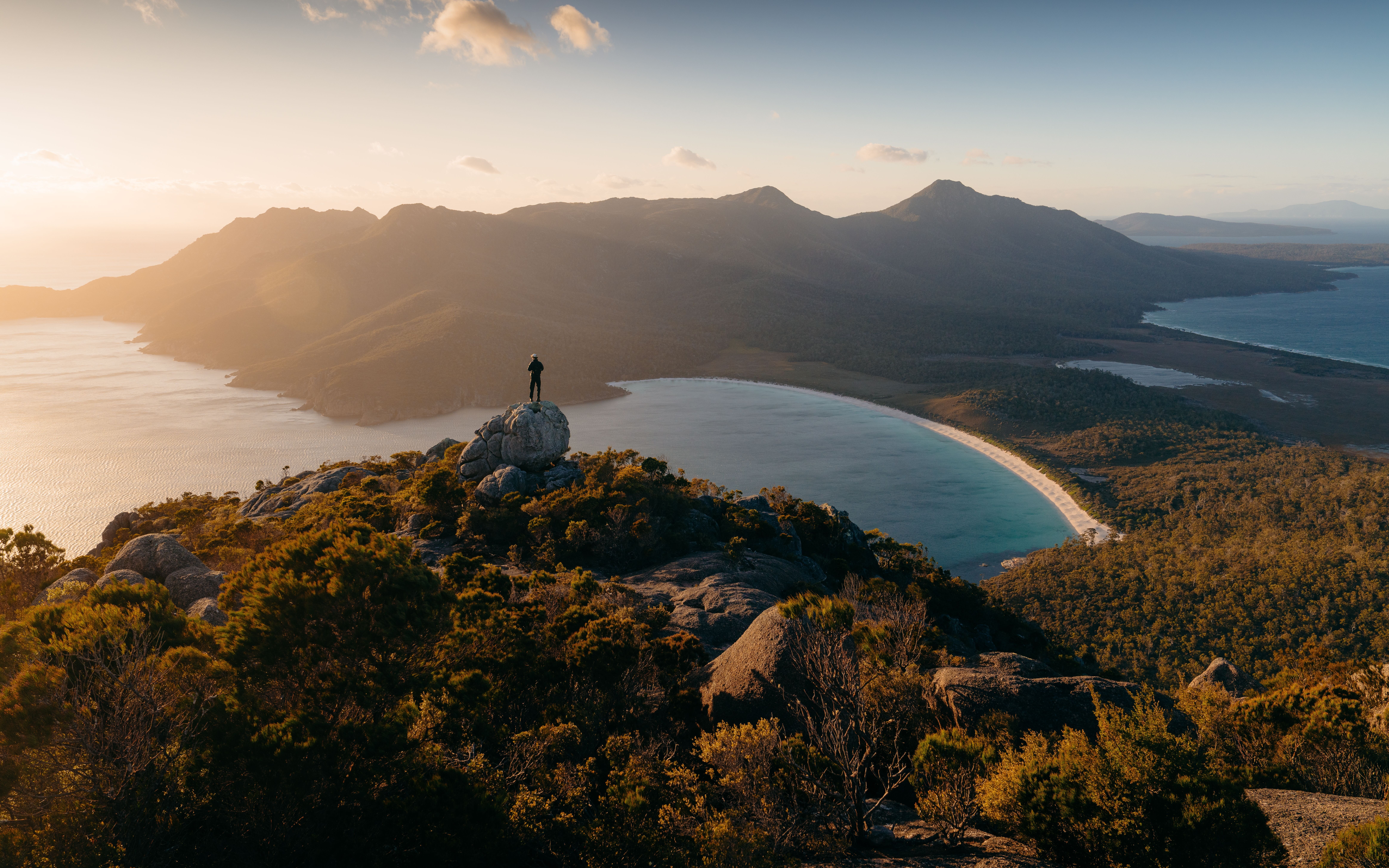 Person on a granite outcrop overlooking Wineglass Bay, Freycinet National Park, Tasmania