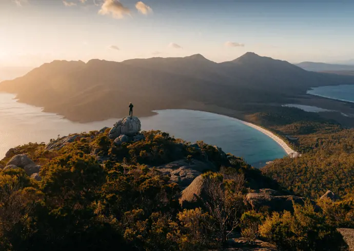 Person on a granite outcrop overlooking Wineglass Bay, Freycinet National Park, Tasmania