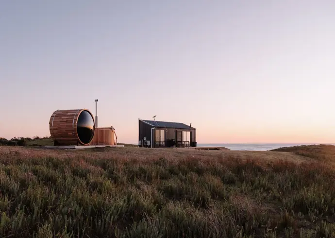 A barrel sauna and small cabin overlooking the sea at Red Rock Hut, King Island, Tasmania
