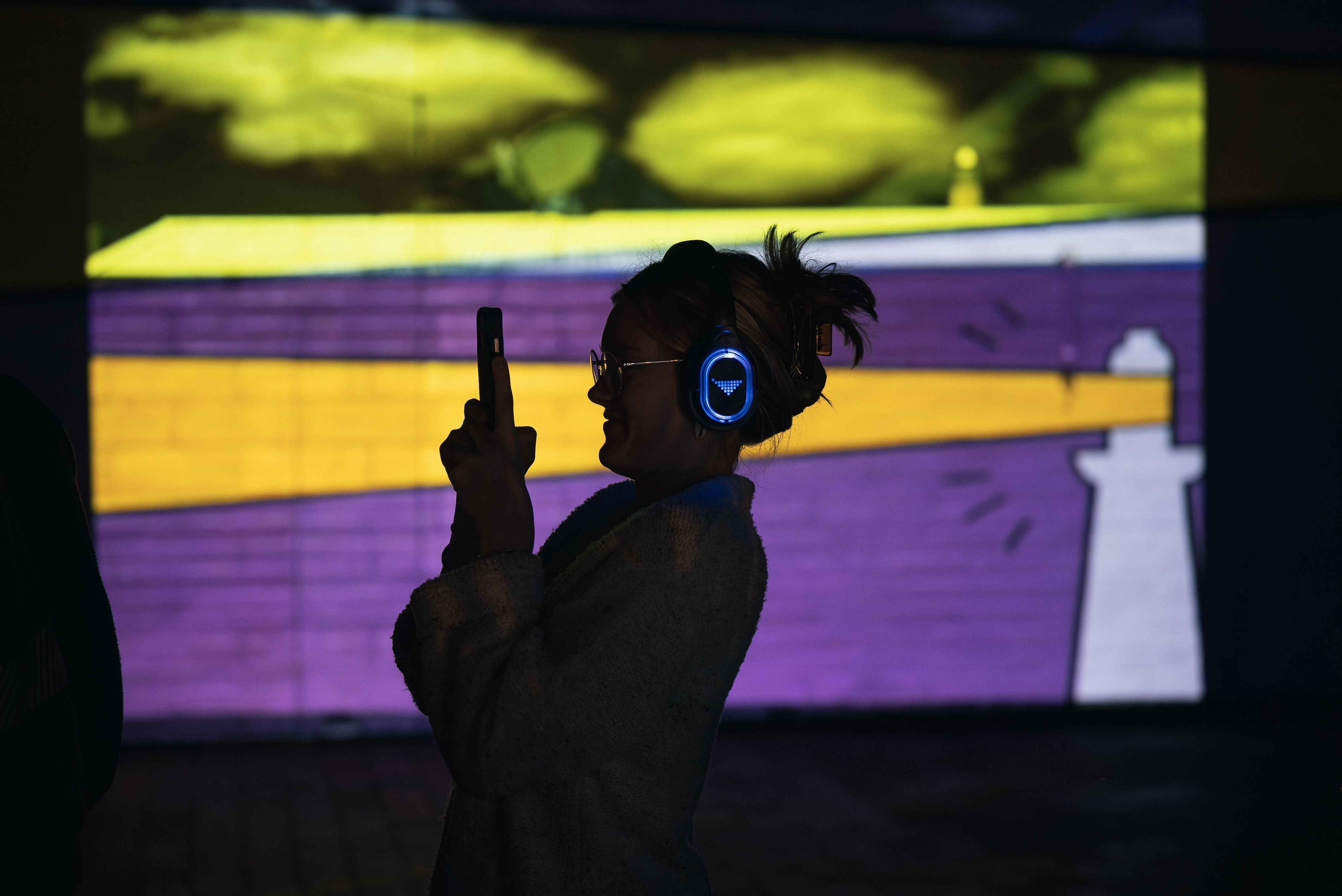 A visitor with headphones taking a photo at the immersive Permission to Trespass event in ArtsCape, Wynyard, Tasmania
