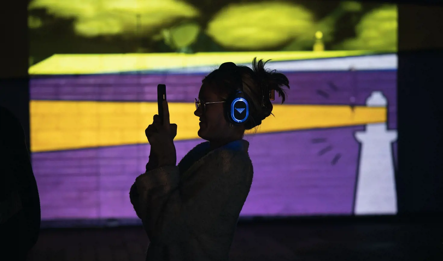 A visitor with headphones taking a photo at the immersive Permission to Trespass event in ArtsCape, Wynyard, Tasmania