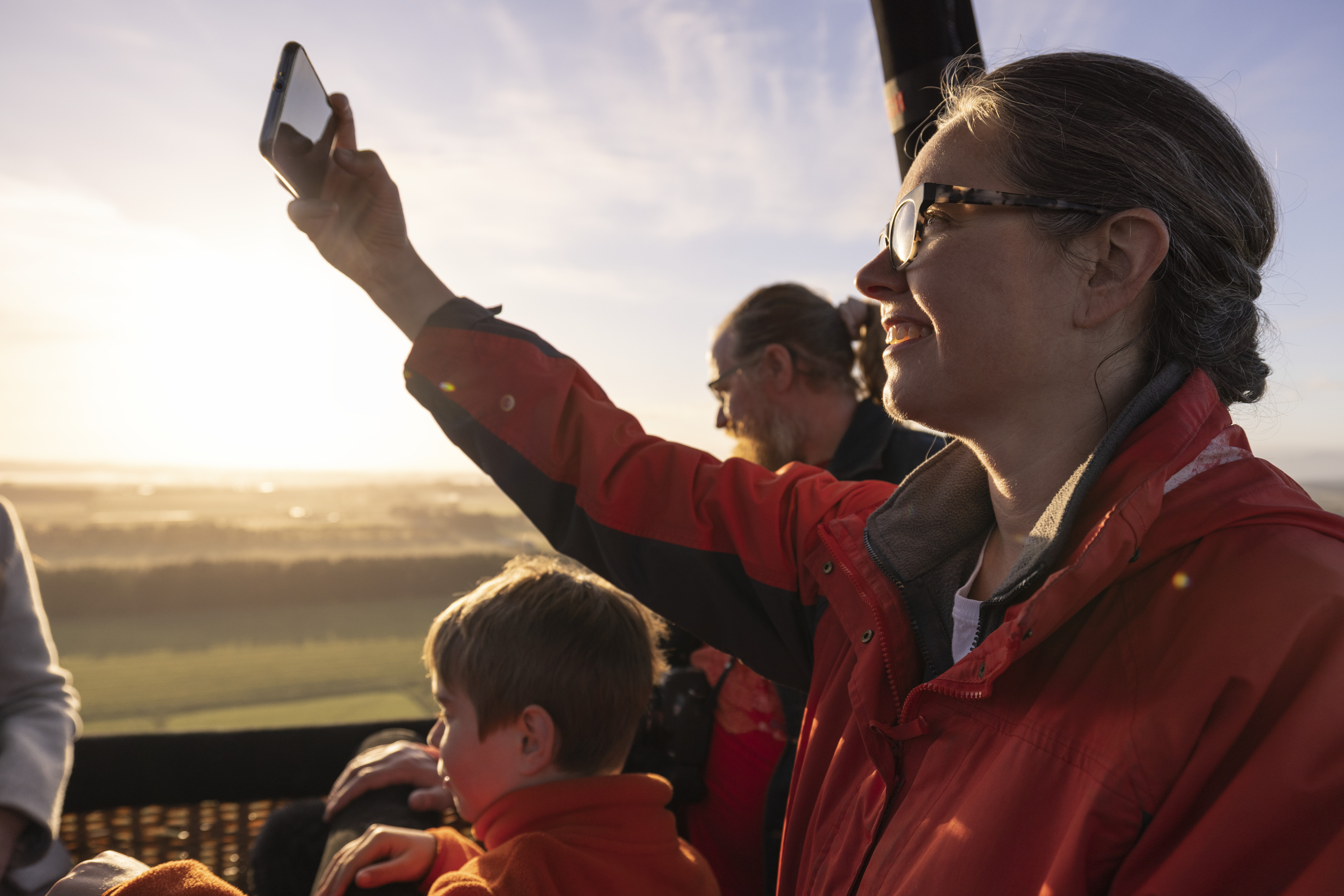 Passengers in a hot air balloon basket with one taking a photo on a phone, Launceston, Tasmania