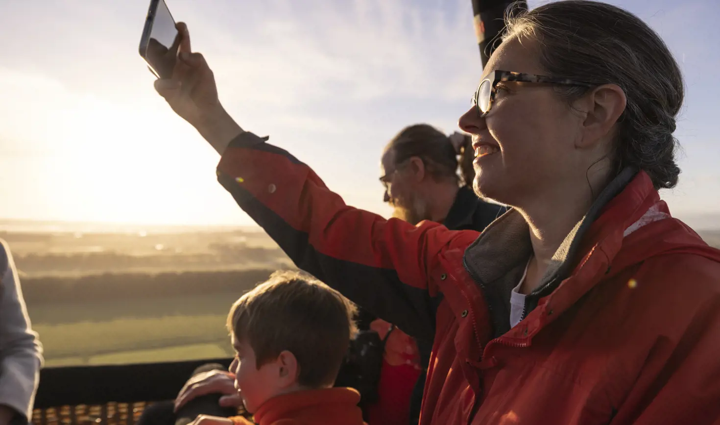 Passengers in a hot air balloon basket with one taking a photo on a phone, Launceston, Tasmania