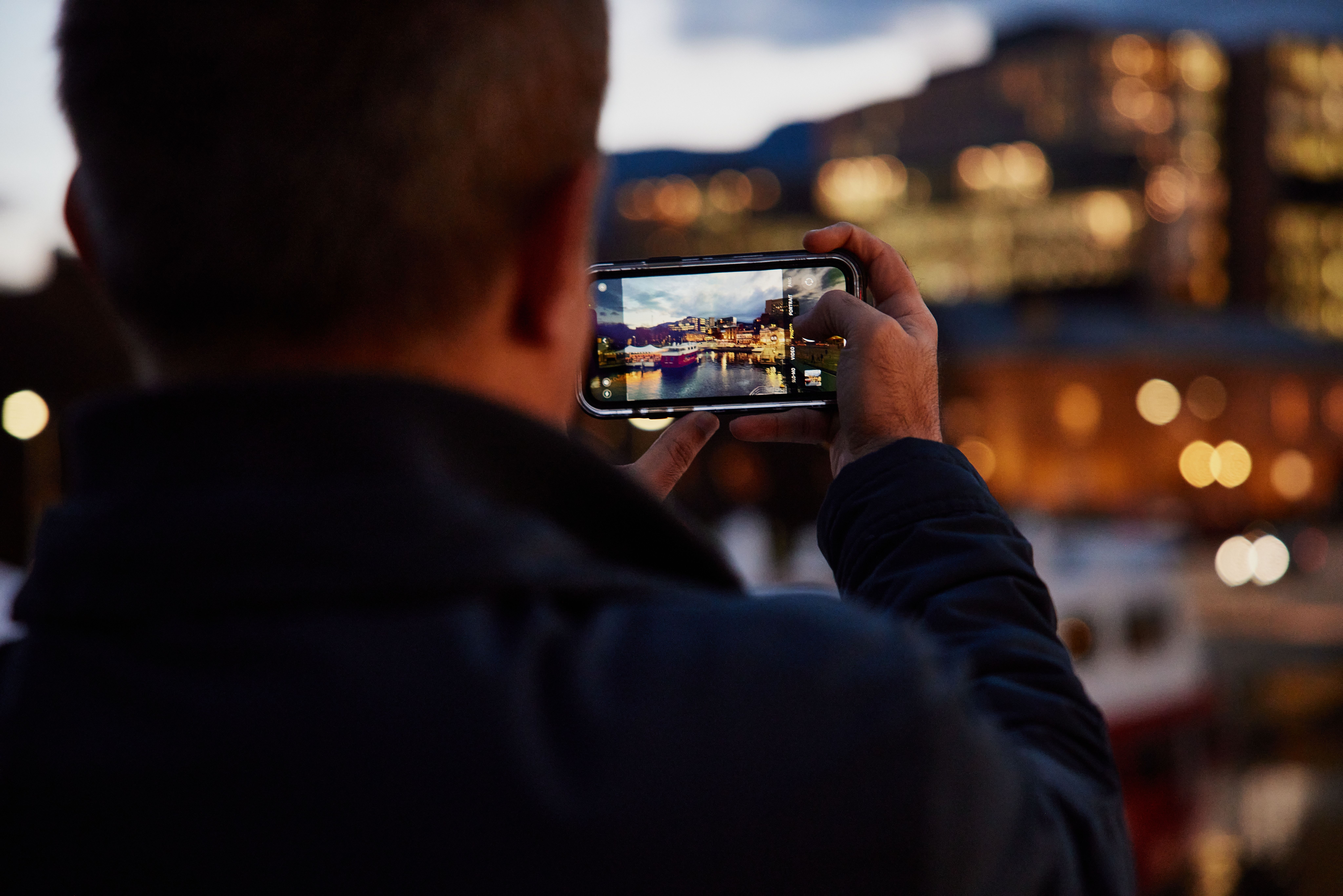 A photographer capturing the Hobart waterfront at twilight on a phone, Hobart, Tasmania