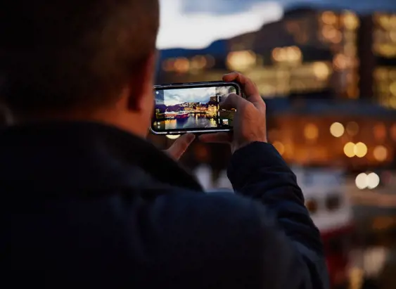 A photographer capturing the Hobart waterfront at twilight on a phone, Hobart, Tasmania