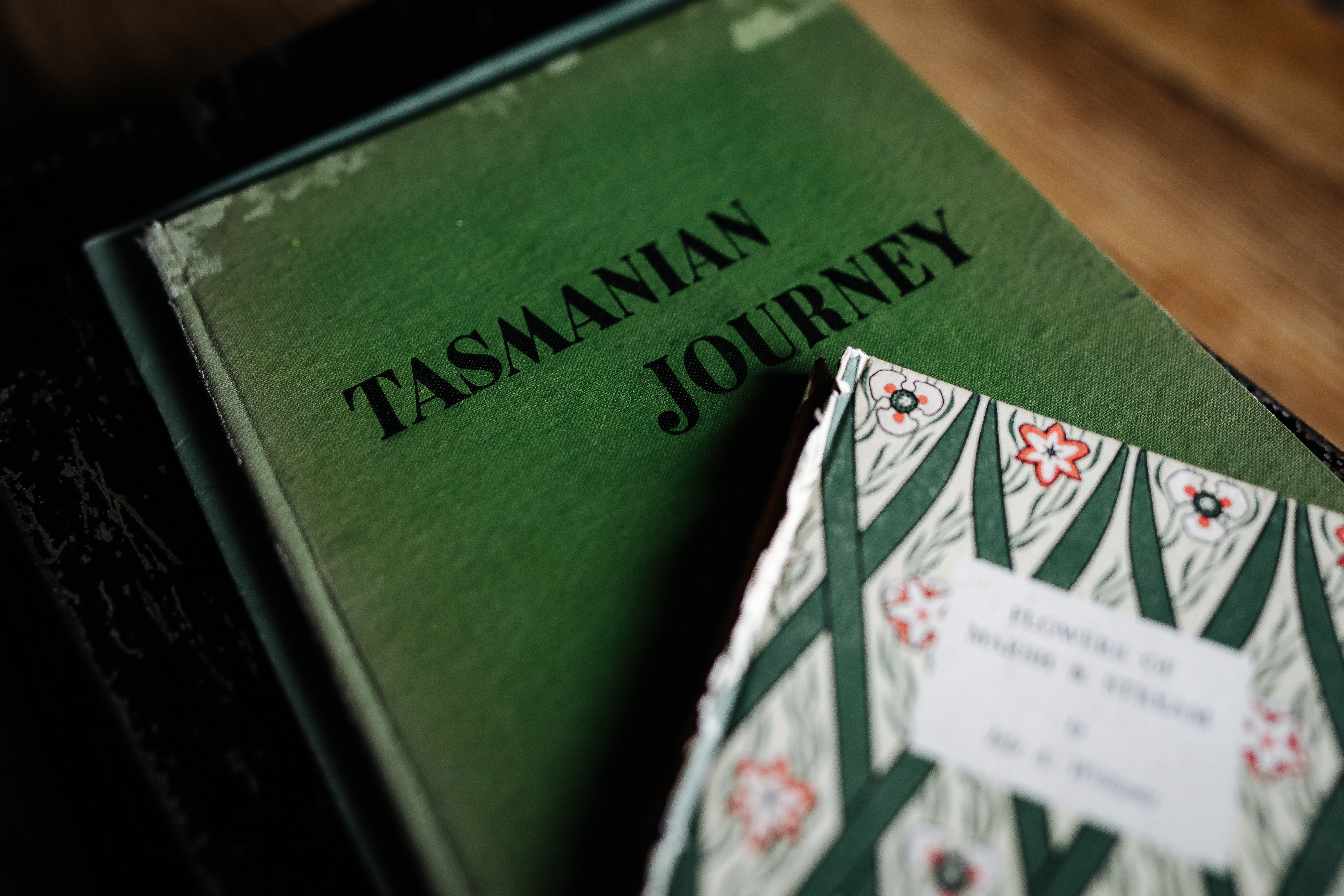 A vintage book titled "Tasmanian Journey" beside a book with a decorative floral cover