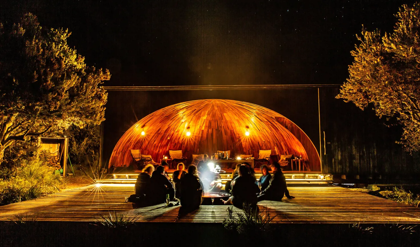 People sitting around an open fire at krakani lumi standing camp on wukalina Walk, wukalina / Mount William National Park
