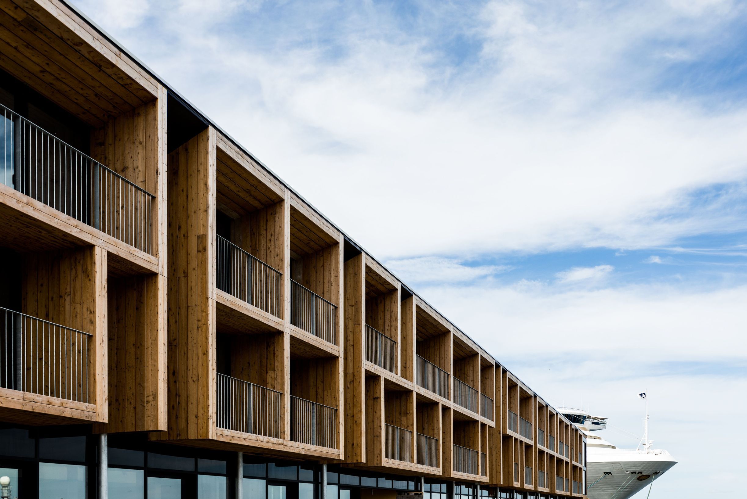 Timber balconies along the MACq01 hotel facade with a cruise ship docked behind