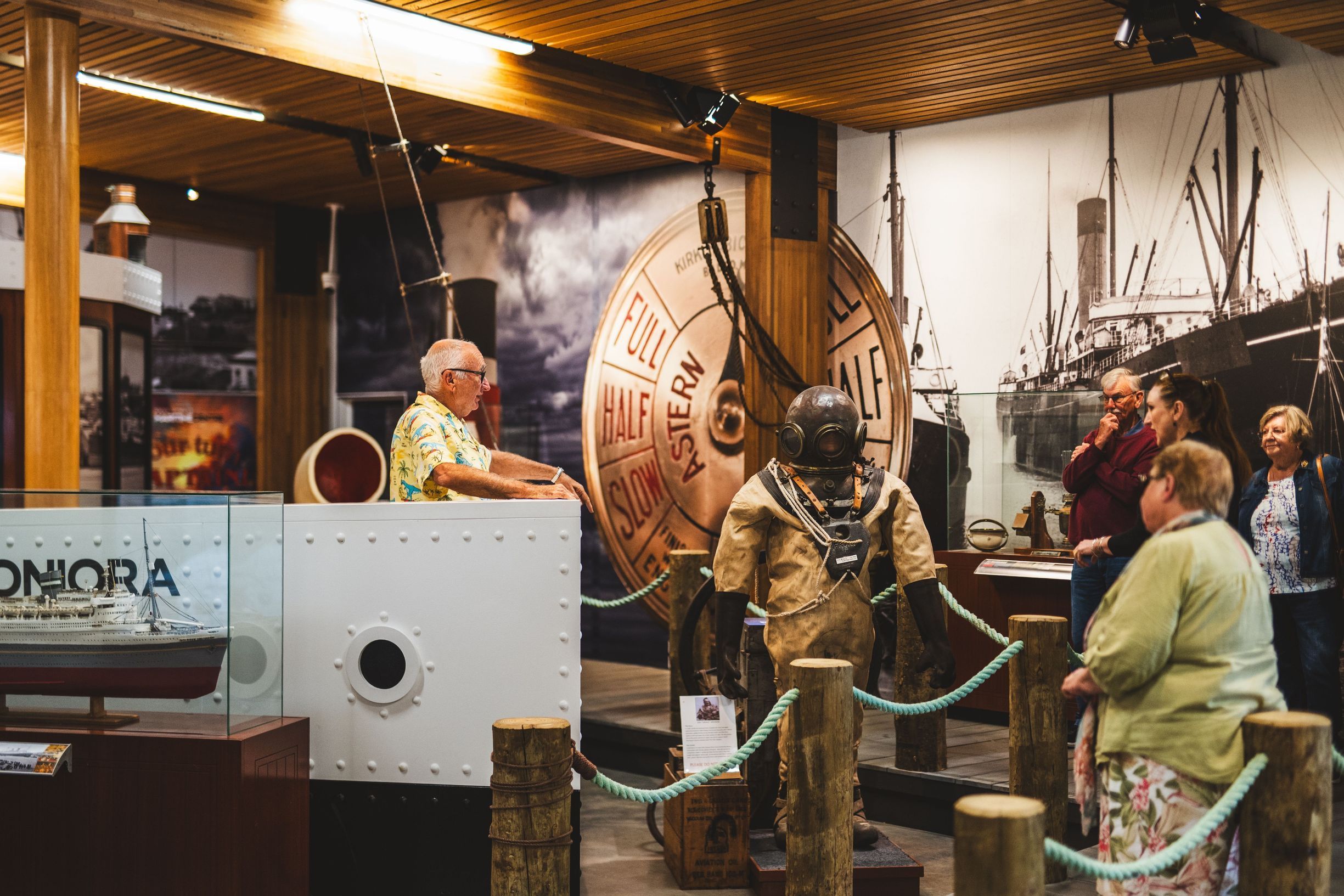 Visitors viewing a vintage diving suit and engine telegraph display at Bass Strait Maritime Museum
