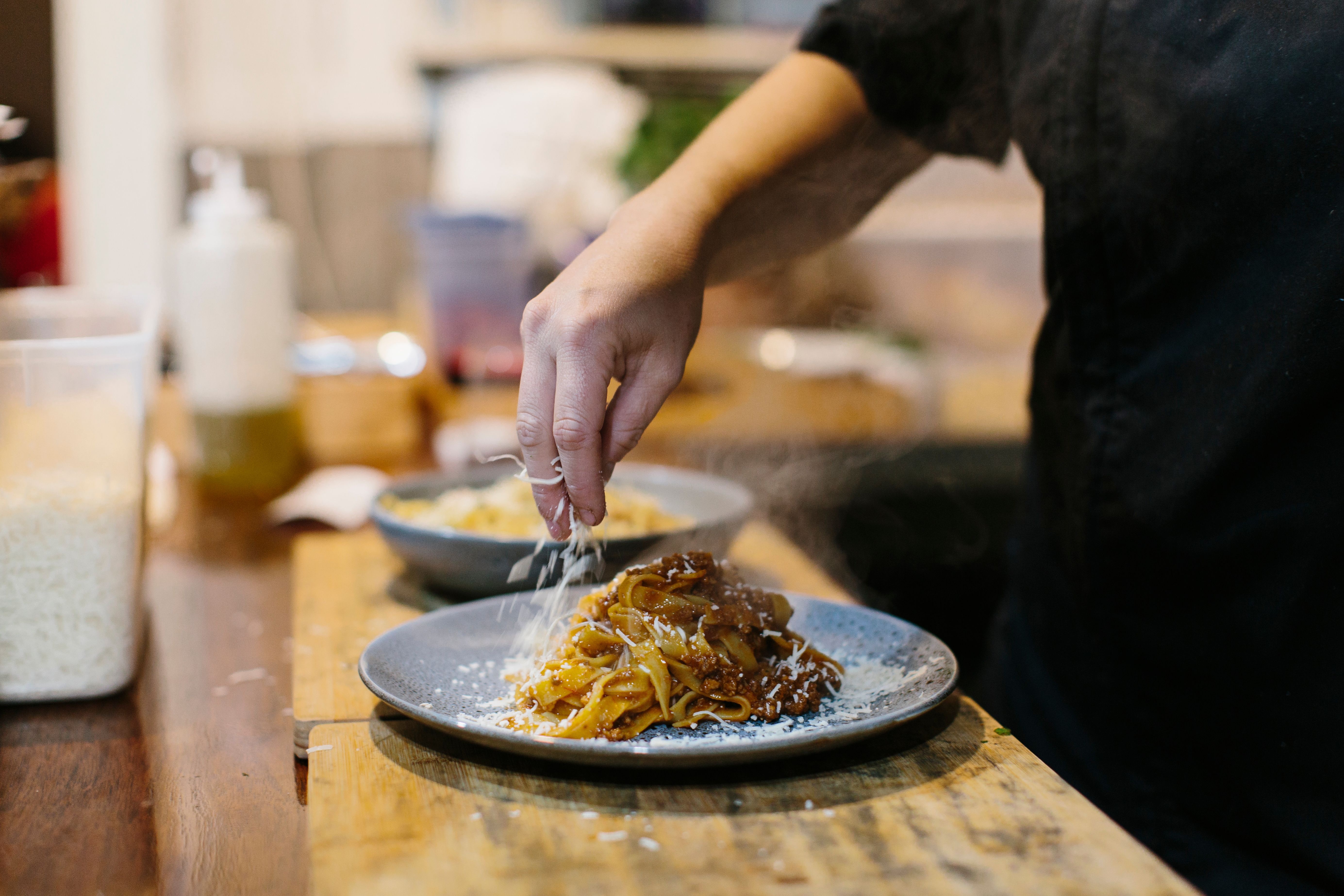 Cheese being grated over a plate of pasta at Pizzirani's Cucina, Devonport, Tasmania