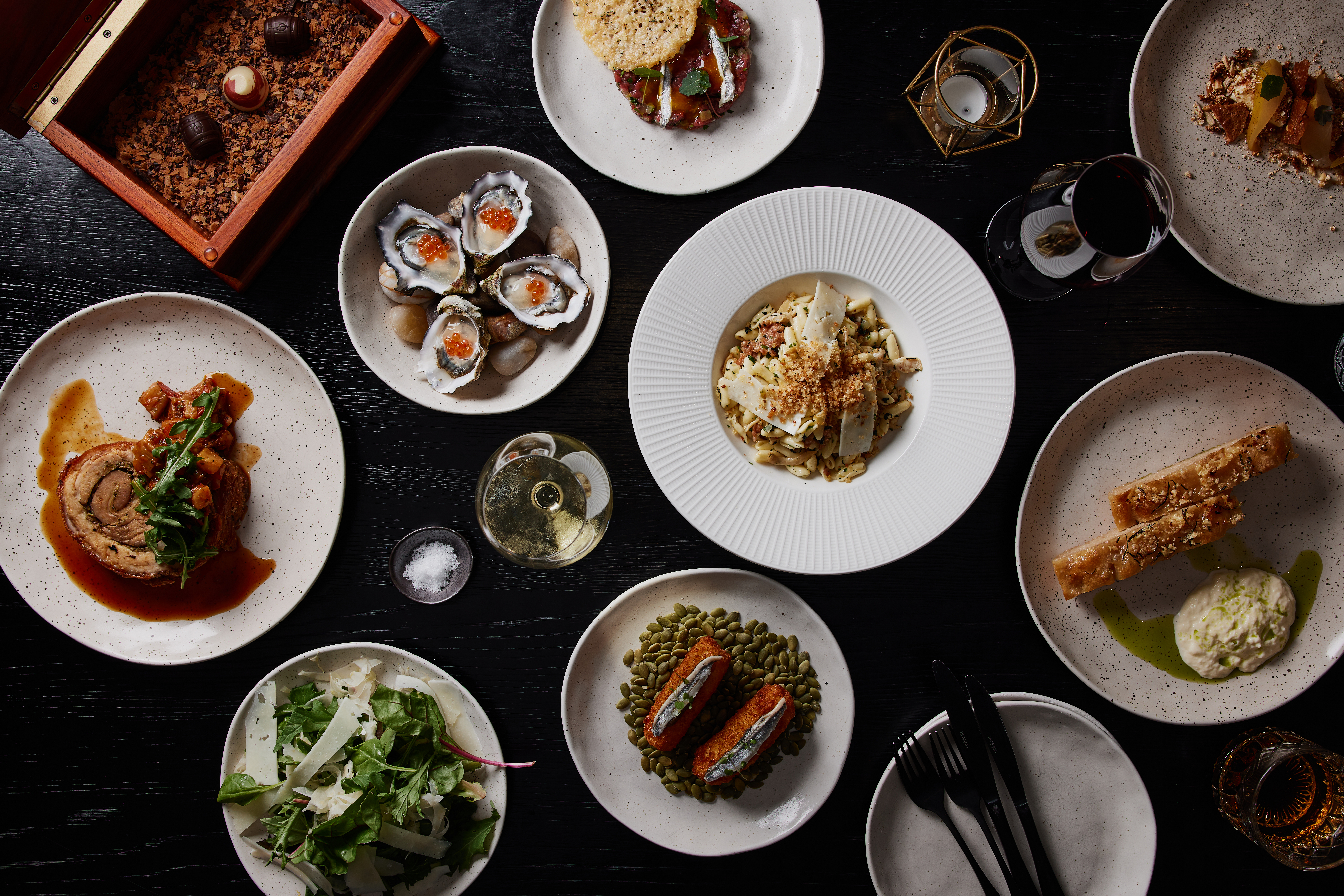 A spread of plated dishes including oysters, salad and wine at Mövenpick Hotel Hobart, Tasmania