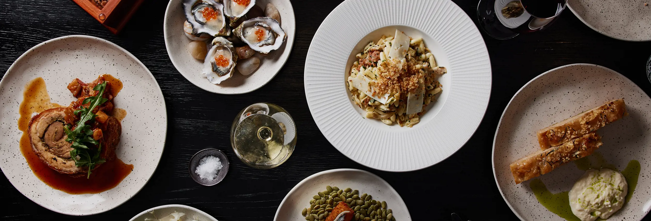 A spread of plated dishes including oysters, salad and wine at Mövenpick Hotel Hobart, Tasmania