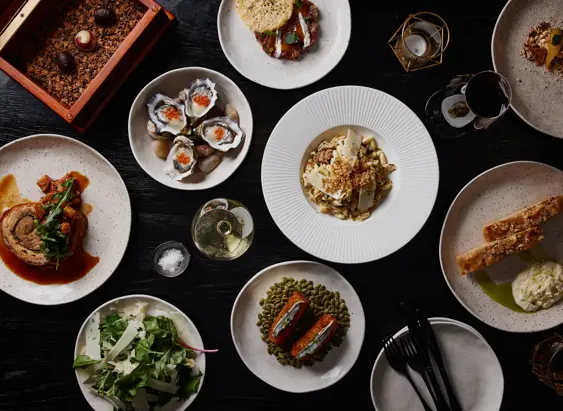 A spread of plated dishes including oysters, salad and wine at Mövenpick Hotel Hobart, Tasmania