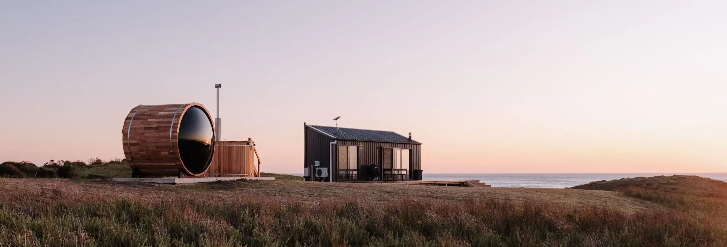 A barrel sauna and small cabin overlooking the sea at Red Rock Hut, King Island, Tasmania