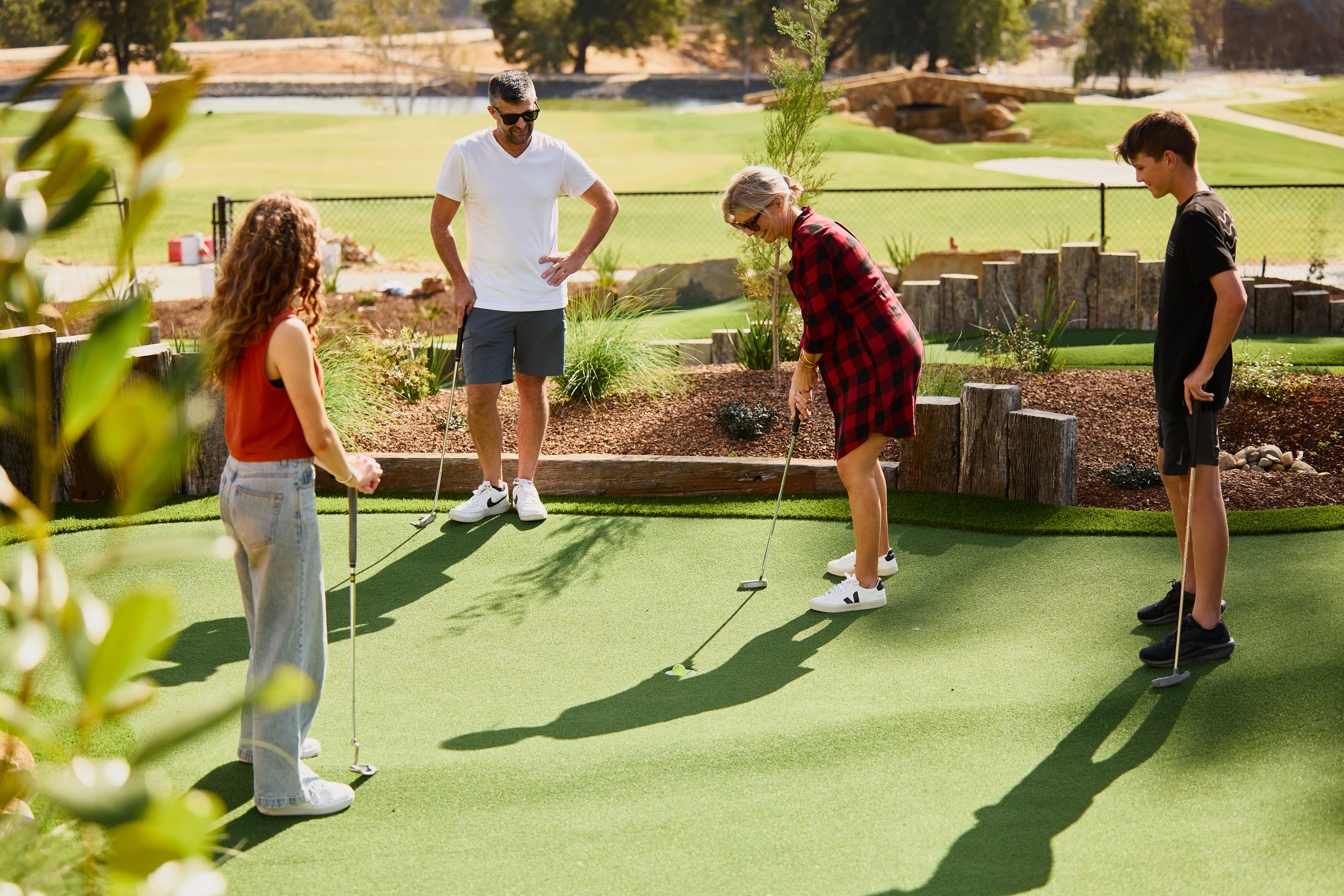Four people putting on an outdoor mini-golf course at The Range, Country Club Tasmania, Prospect Vale, Tasmania