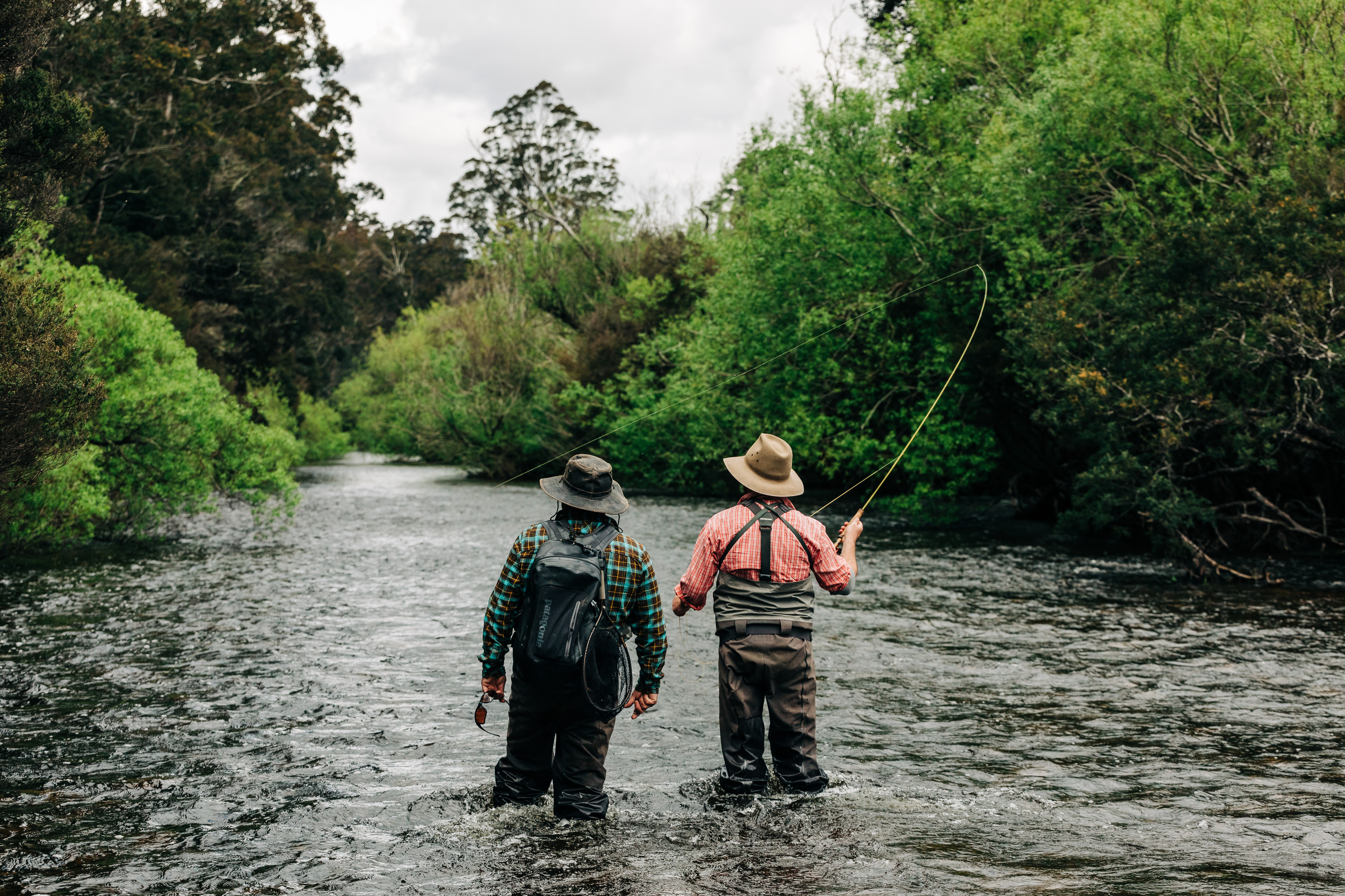 Two anglers fly fishing in St Patricks River with one casting a line, near Launceston, Tasmania