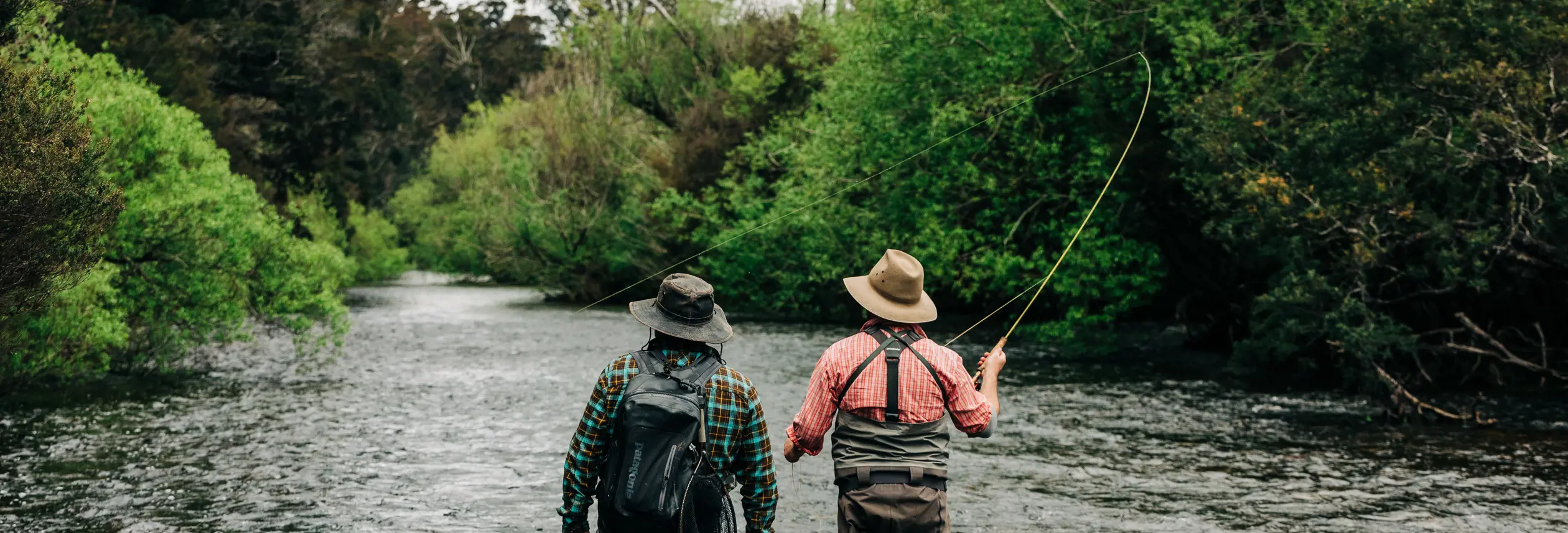 Two anglers fly fishing in St Patricks River with one casting a line, near Launceston, Tasmania