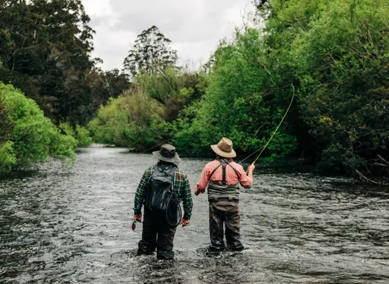 Two anglers fly fishing in St Patricks River with one casting a line, near Launceston, Tasmania