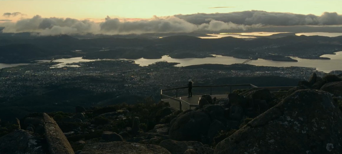 A person at the lookout on kunanyi / Mount Wellington overlooking Hobart and the Derwent in golden light, Tasmania