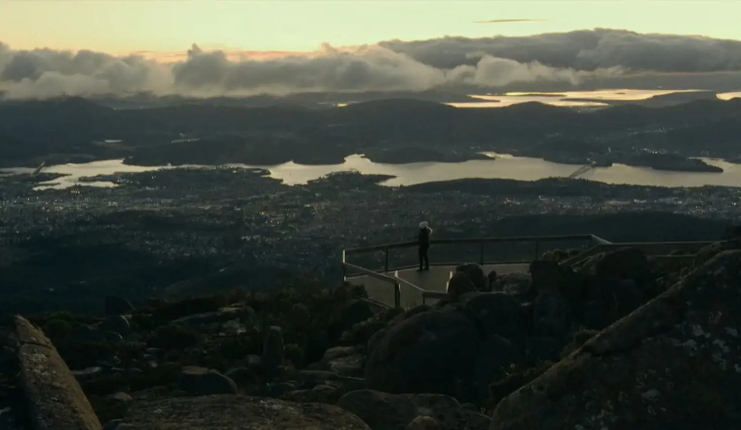 A person at the lookout on kunanyi / Mount Wellington overlooking Hobart and the Derwent in golden light, Tasmania