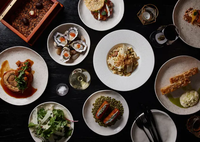 A spread of plated dishes including oysters, salad and wine at Mövenpick Hotel Hobart, Tasmania