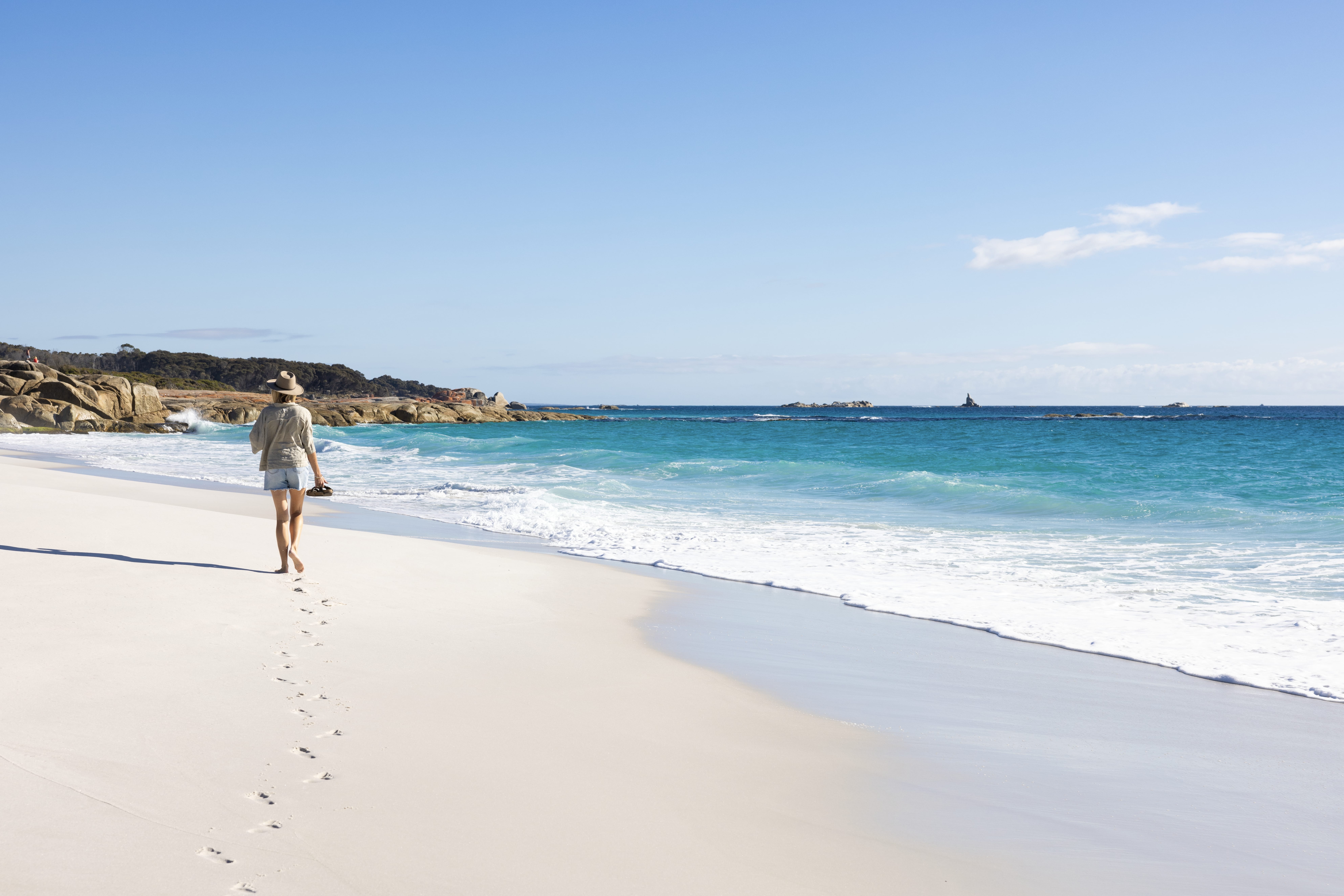 A walker on the white sand beach at Cosy Corner, larapuna / Bay of Fires Conservation Area, Tasmania
