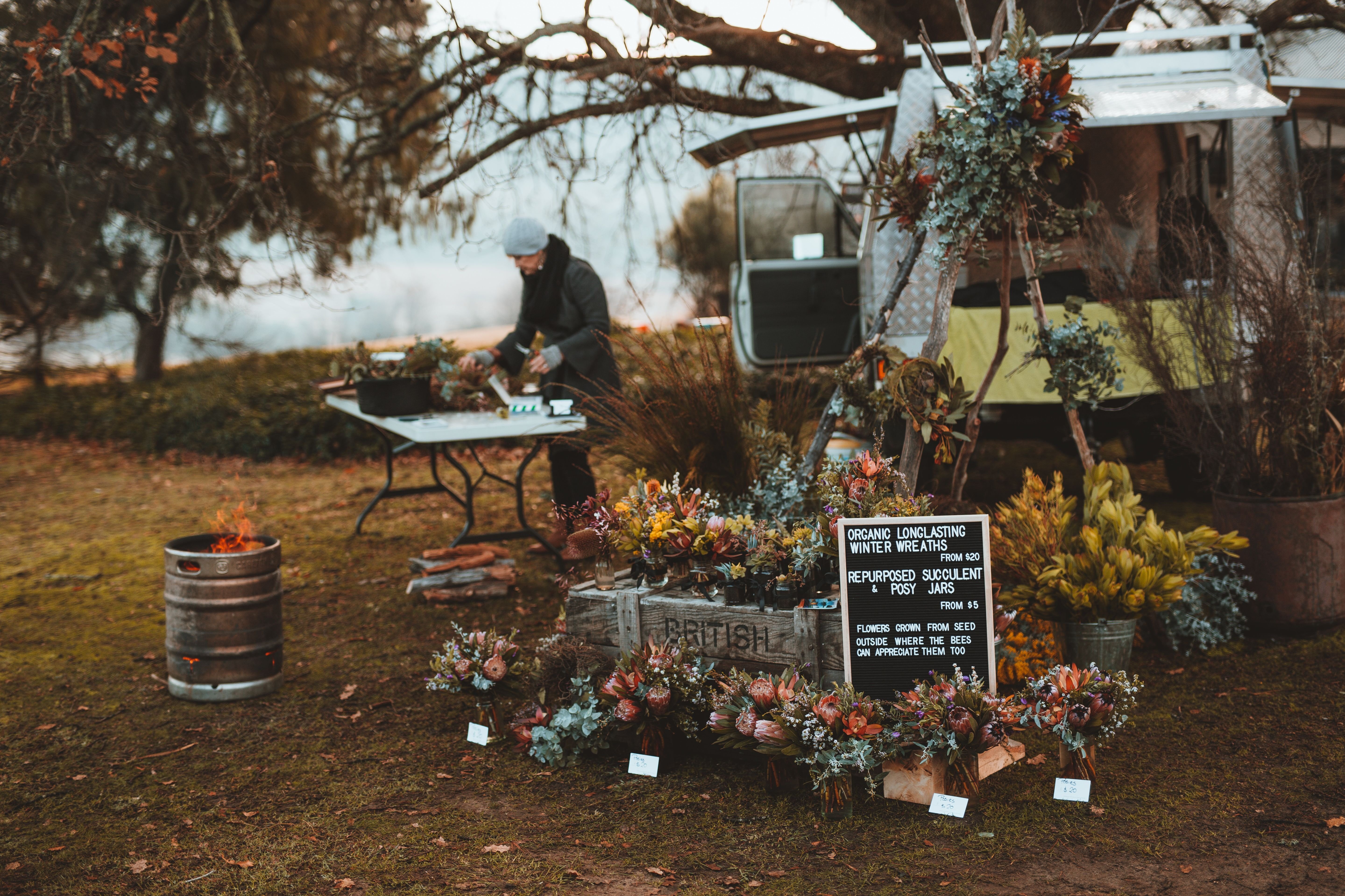 A stallholder preparing winter wreaths and posy jars at Festival of Voices Farmers Market, Twamley Farm, Buckland, Tasmania