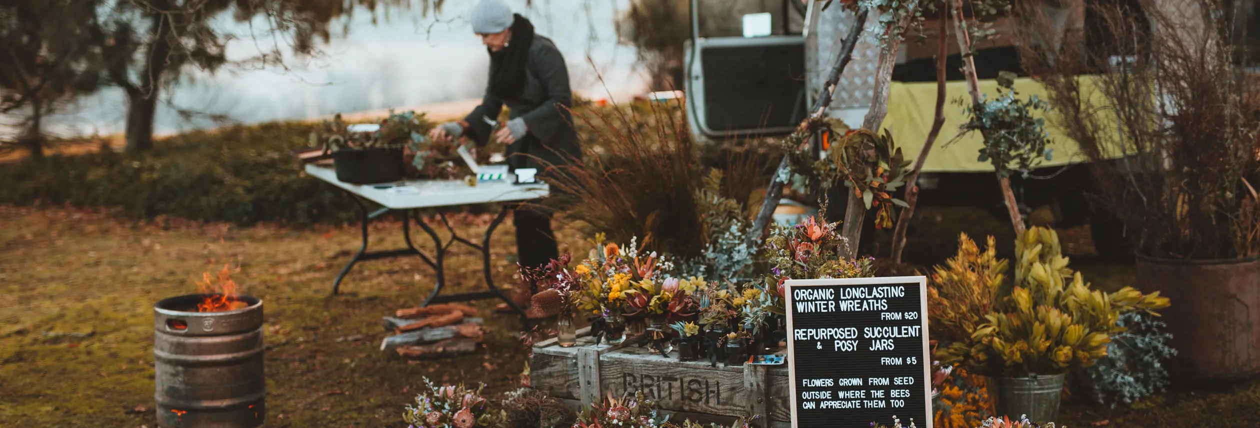 A stallholder preparing winter wreaths and posy jars at Festival of Voices Farmers Market, Twamley Farm, Buckland, Tasmania