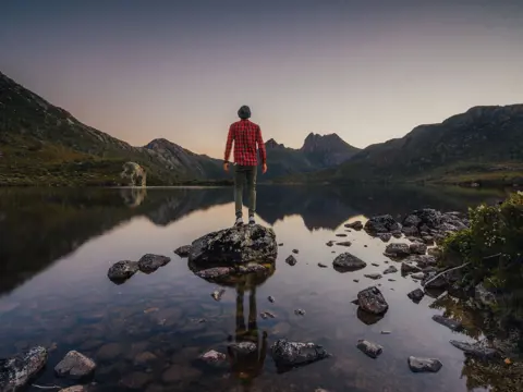 A person on a rock at Dove Lake looking to Cradle Mountain, Cradle Mountain-Lake St Clair National Park, Tasmania
