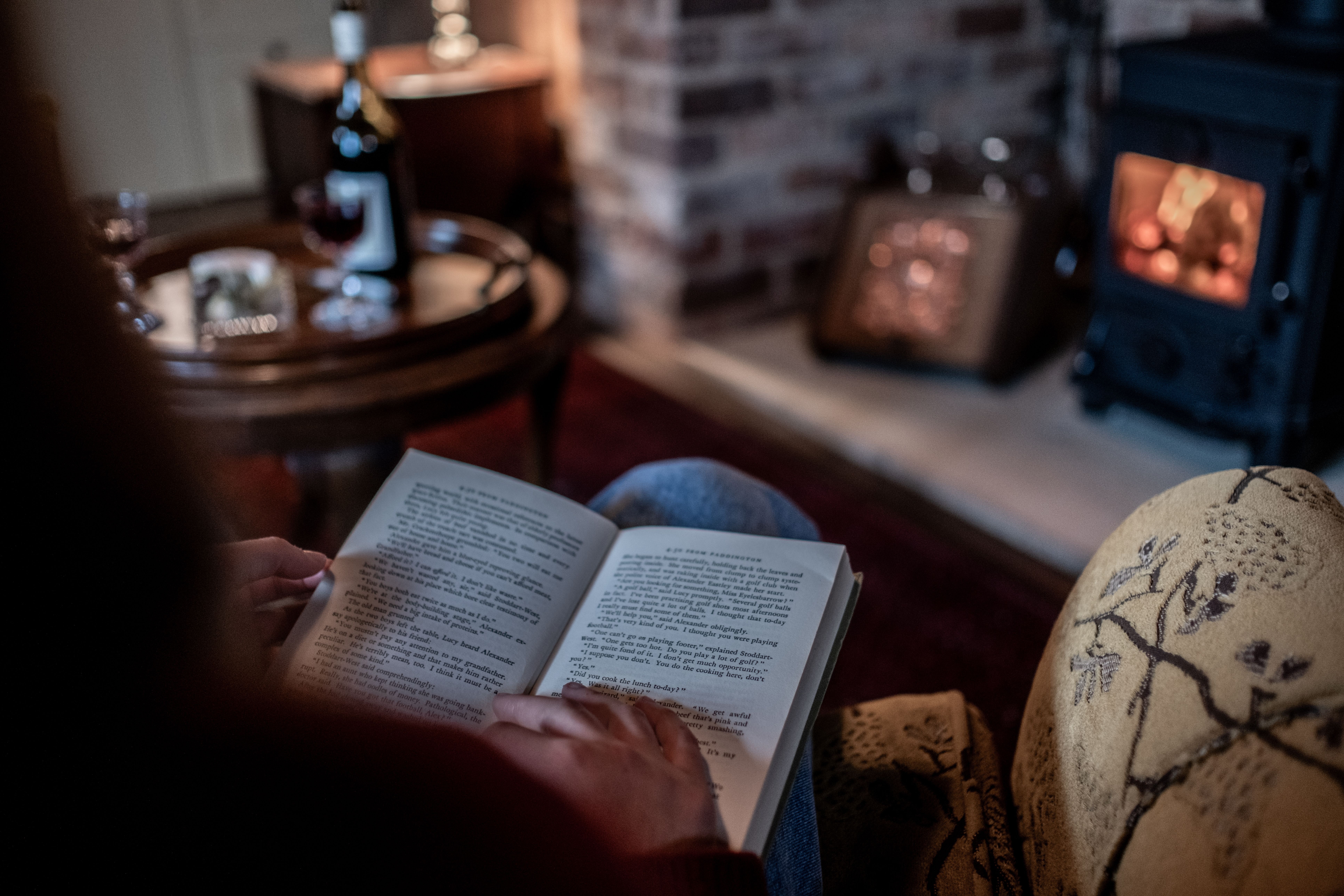 A guest reading a book by the wood fire at Old Bishop's Quarters, Fitzroy Place, Sandy Bay