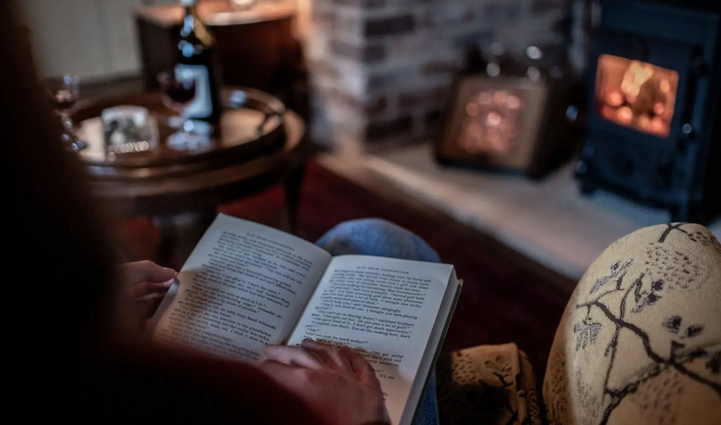 A guest reading a book by the wood fire at Old Bishop's Quarters, Fitzroy Place, Sandy Bay