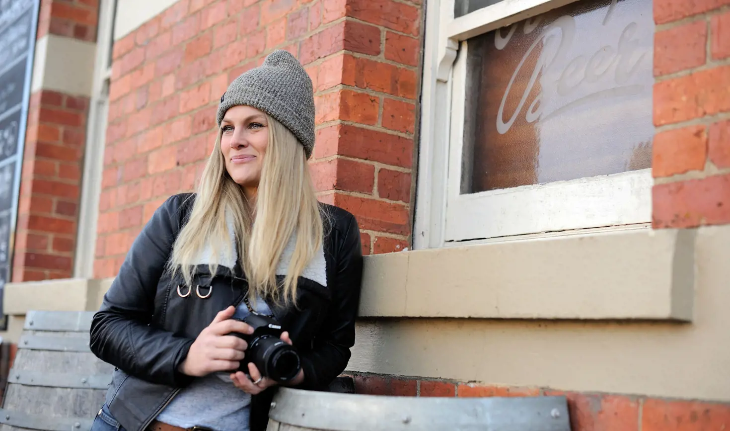 A photographer with a camera leaning against the brick wall of the Empire Hotel, Deloraine