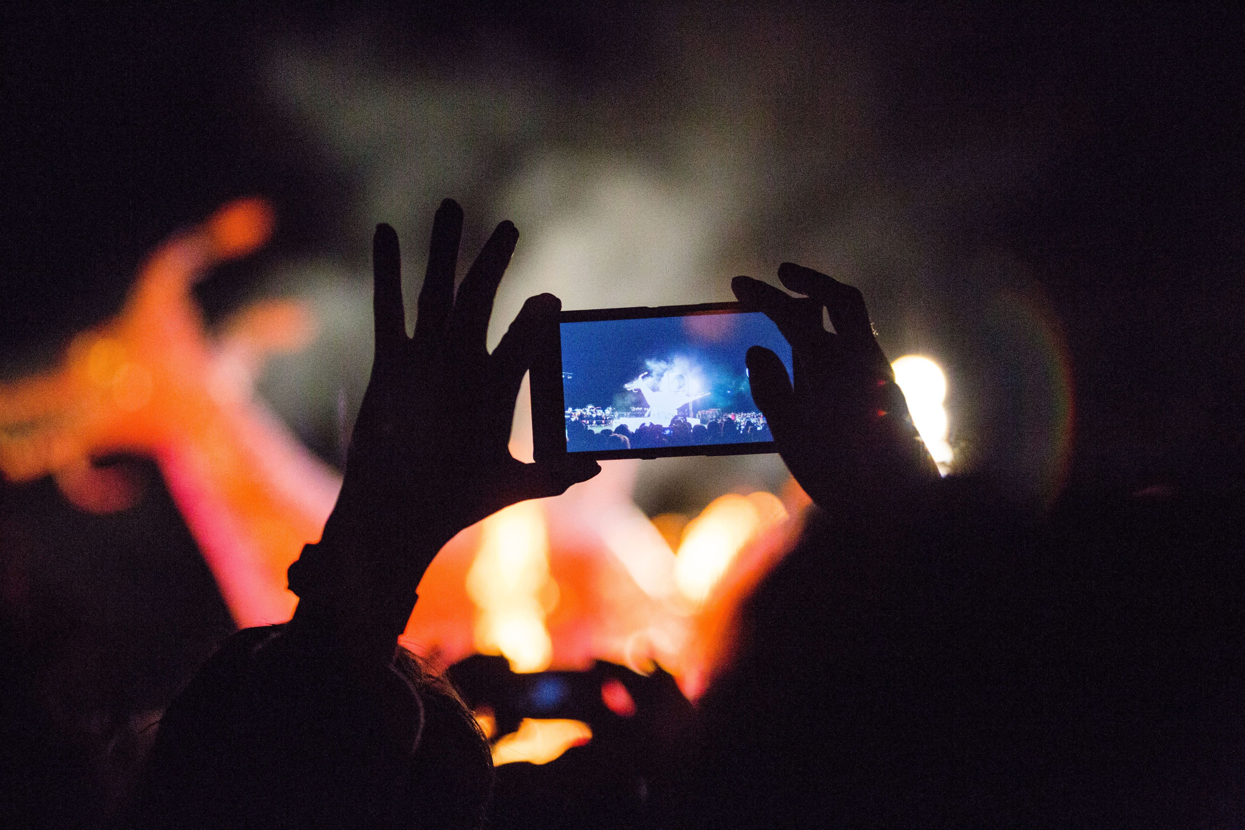 A spectator captures Dark Mofo's The Burning fire ceremony on a smartphone, Hobart