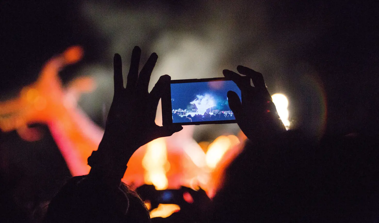 A spectator captures Dark Mofo's The Burning fire ceremony on a smartphone, Hobart