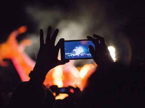 A spectator captures Dark Mofo's The Burning fire ceremony on a smartphone, Hobart