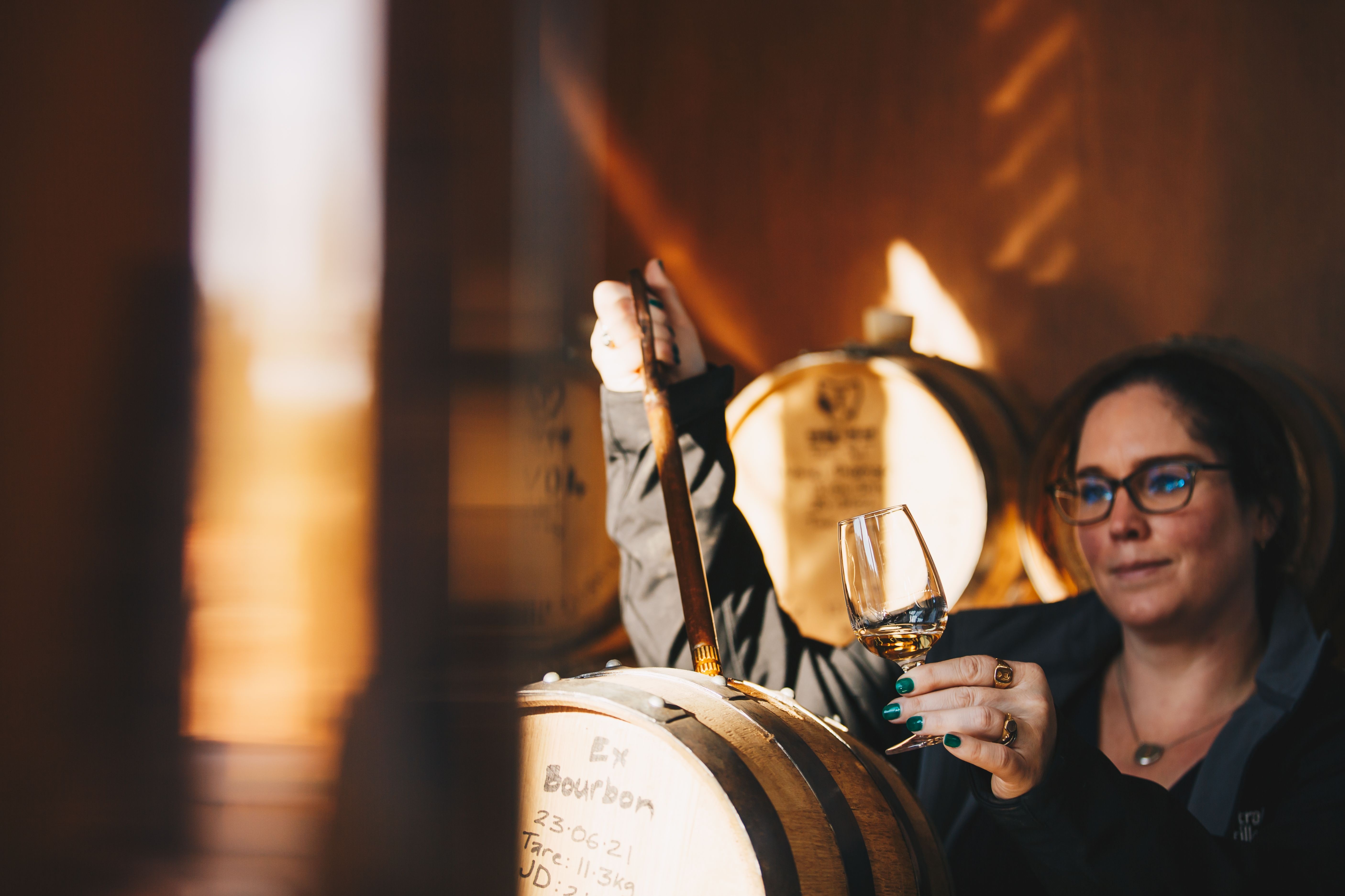 A distiller drawing whisky from a barrel at Killara Distillery, Richmond