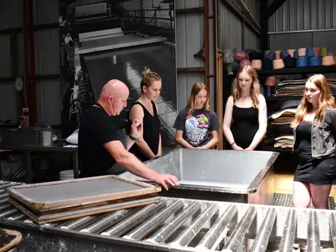 A papermaker demonstrating handmade paper-making to visitors at Creative Paper Tasmania, Wynyard