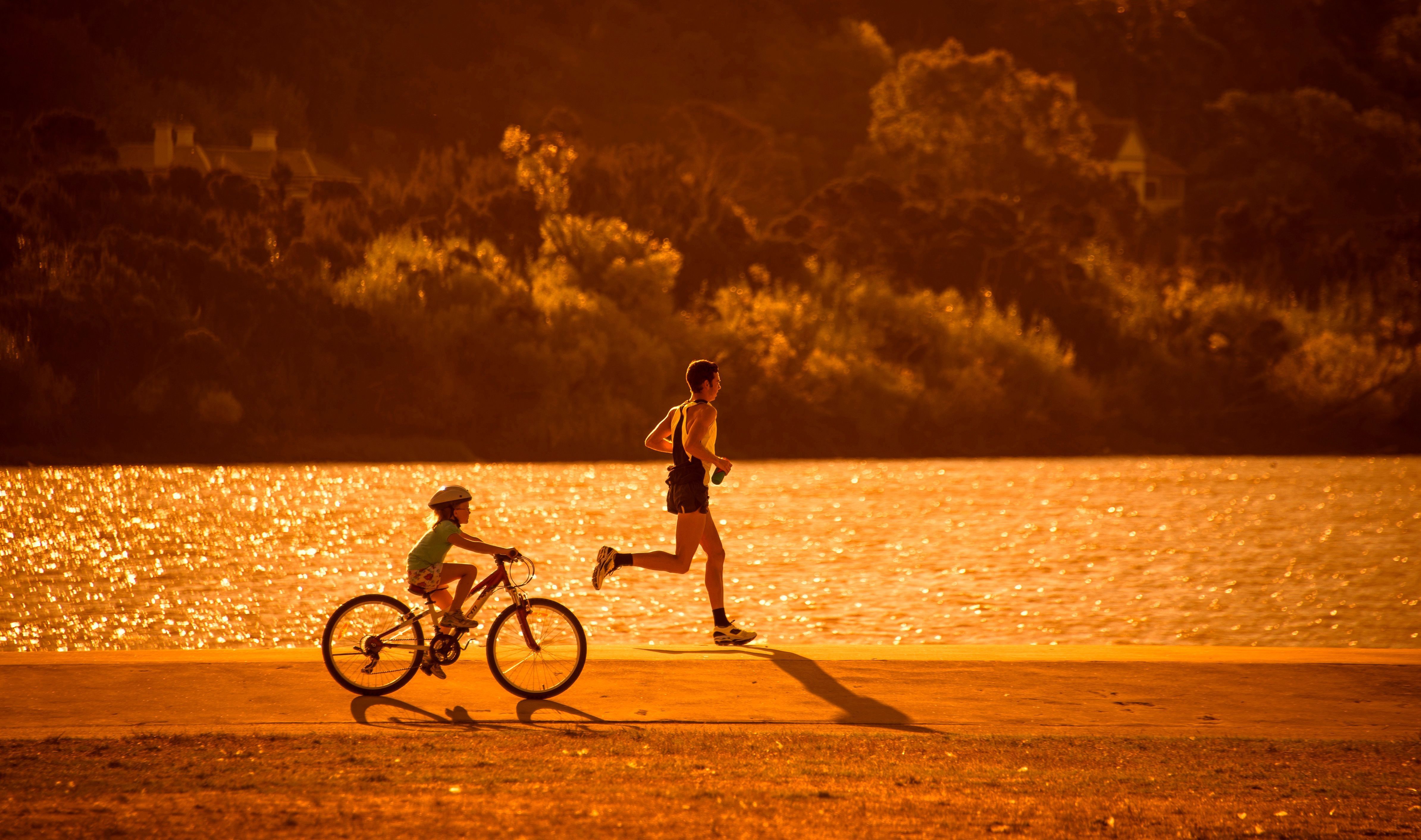 A runner and a child cycling beside the North Esk River at golden hour, Launceston