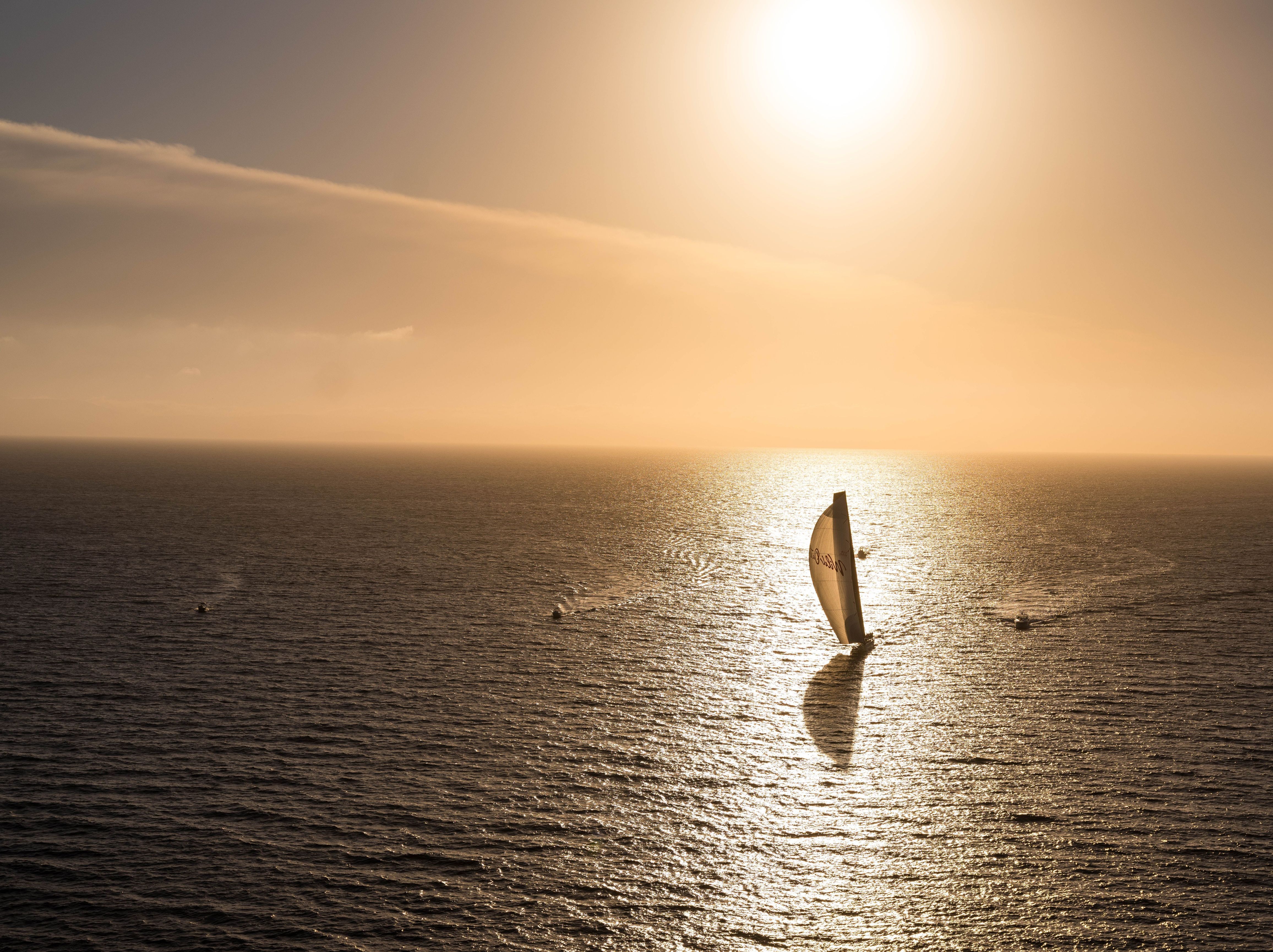 A yacht sailing across open ocean at golden hour during the Sydney to Hobart Yacht Race