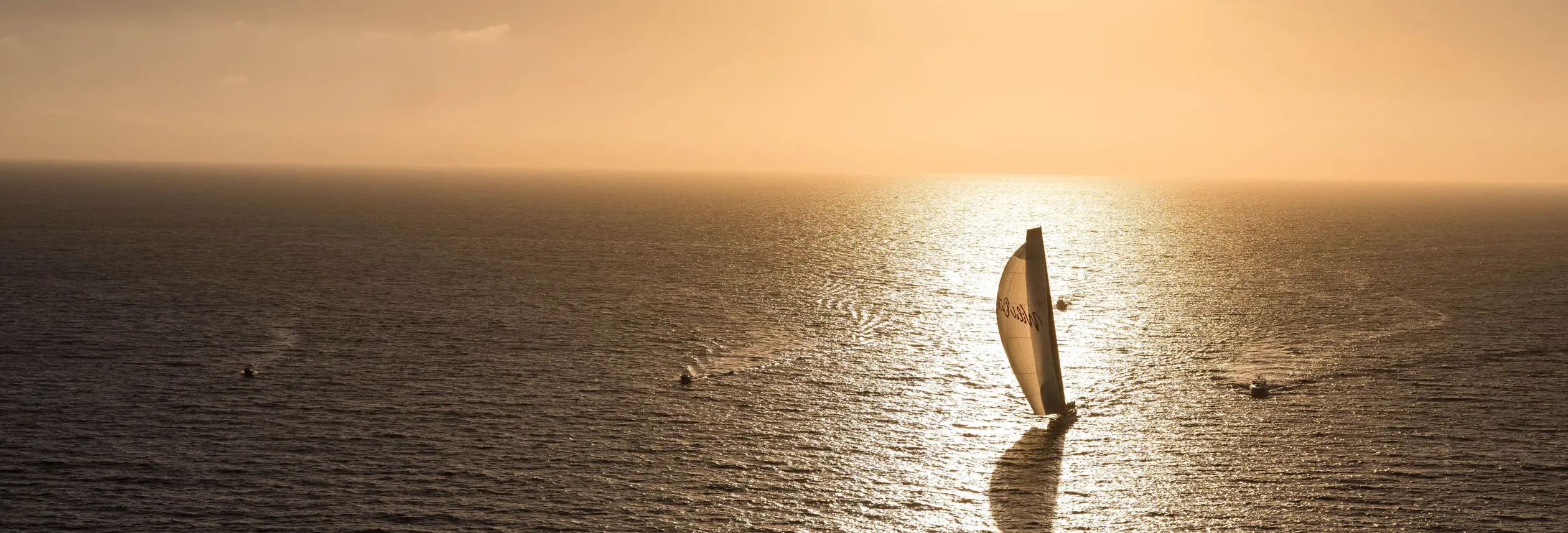 A yacht sailing across open ocean at golden hour during the Sydney to Hobart Yacht Race
